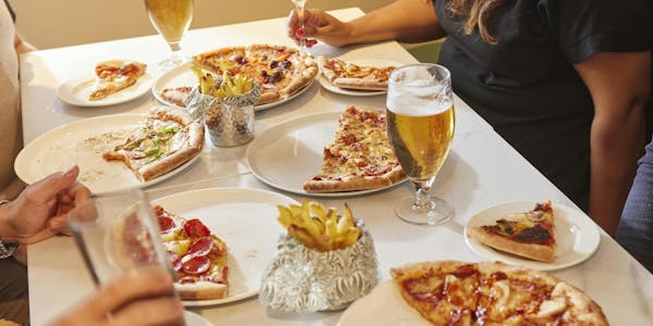Four people eating pizza and drinking beer & prosecco at Super 8 by Wyndham