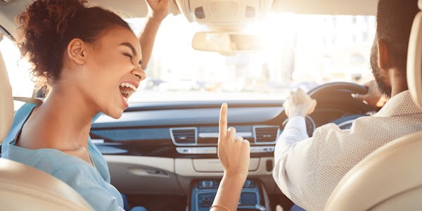 Lady in passenger seat singing at man driver
