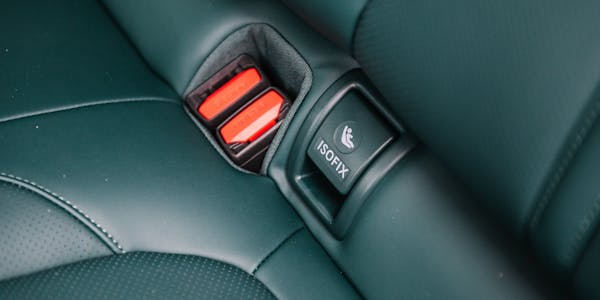 Close-up of Isofix fitting cover and seatbelts in a car.