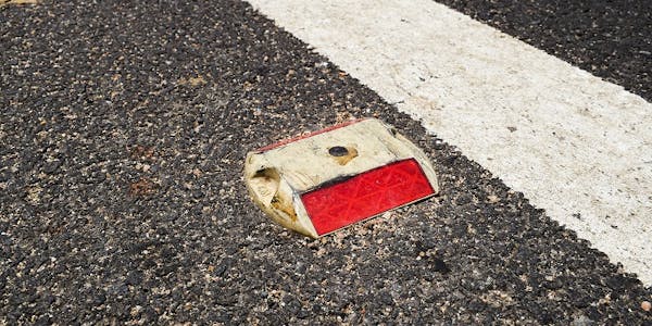 Red motorway stud on black tarmac, near white line